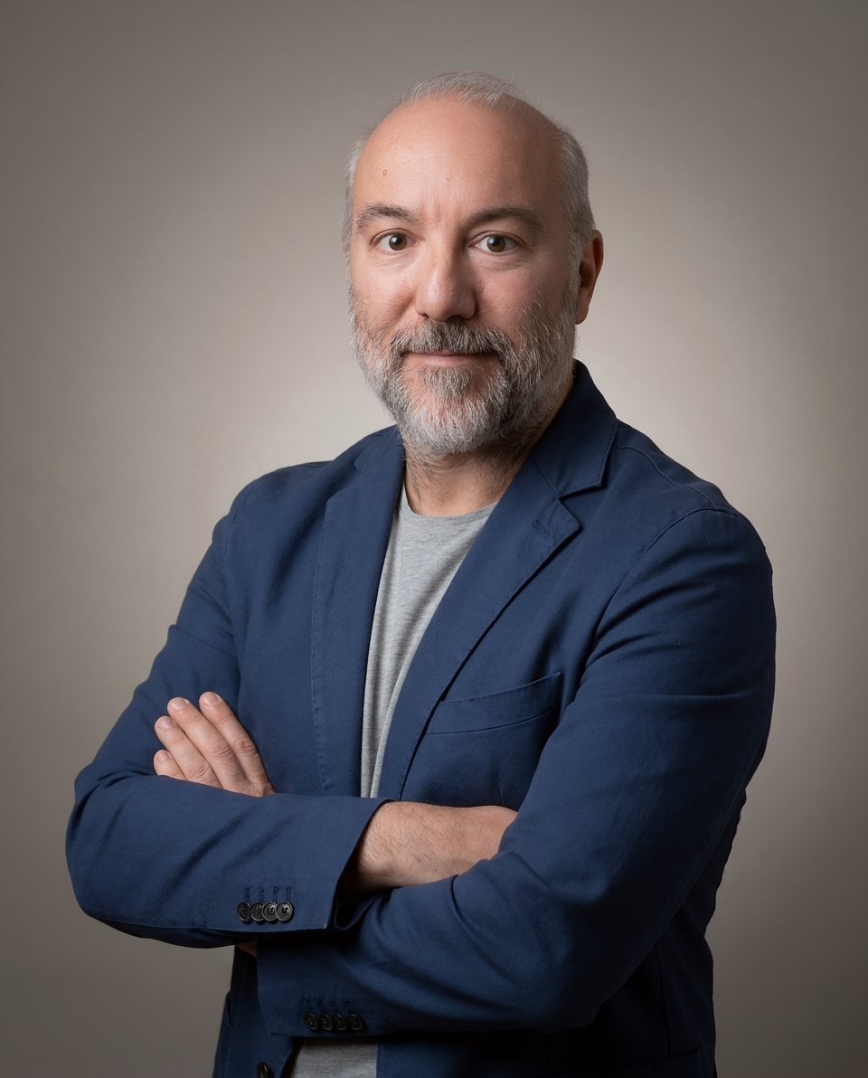 Roberto Cristoferoni, in a navy blazer, arms crossed, against a grey background